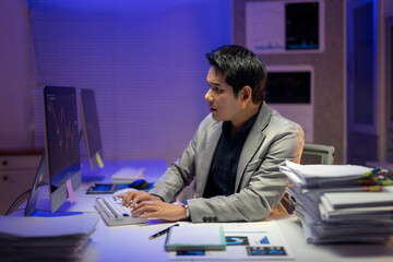 A man is sitting at a desk with a keyboard and a computer monitor