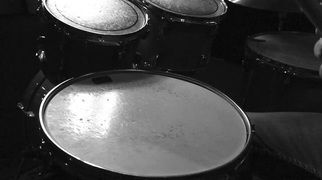 Close up or closeup slow motion footage of a person hitting drums and snare drum with wooden drumsticks. Video is grayscale colored and cinematic. Acoustic drums in a studio indoors with good lights.