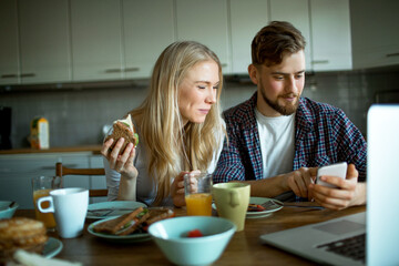 Young couple having breakfast in the morning and using their smart phone