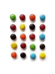 Round multicolored chocolate candies isolated on white background arranged in rectangular, top view, flat lay. Bonbon sweets, dragee