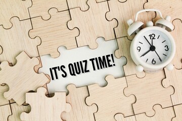 bell clock and wooden puzzle with the word It's Quiz Time. the concept of answering quizzes or quiz...