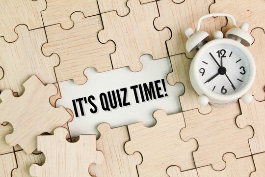 bell clock and wooden puzzle with the word It's Quiz Time. the concept of answering quizzes or quiz games
