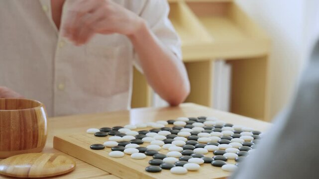 Close up of young men play board game Go during competition in community. 