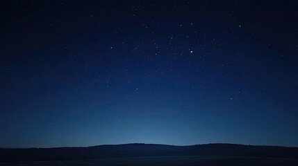 Starry night sky over serene landscape with distant hills and calm atmosphere