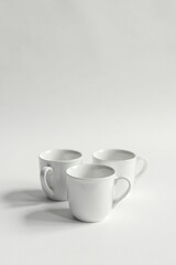 Three Simple White Porcelain Mugs Arranged on a Plain White Surface, Minimalist Style Product Photography for Mockups and Branding