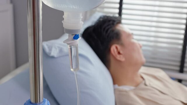 Close up of mature male patient getting saline solution in hospital ward.