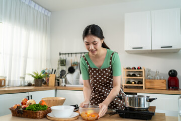 Asian young woman cooking healthy foods in kitchen in morning at home. 