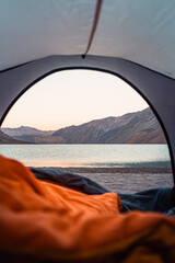lake sight from a tent at the sunrise sleeping in an orange sleepingbag in Cajón del Maipo, Chile 