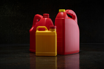 Front view of three different yellow and red plastic motor oil bottles, container with handle and screw cap without label