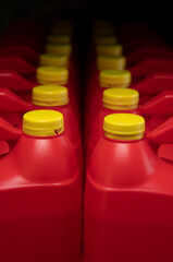 Front view of two columns of red plastic motor oil bottles, container with handle and yellow screw cap without label
