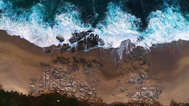 Aerial view of aquamarine ocean waves crashing on the shores of Monterey California