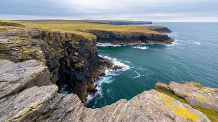 A cliffside view looking down at waves crashing against the rocks.