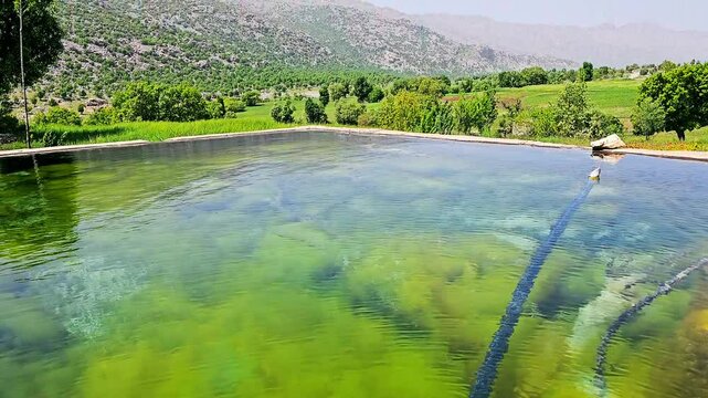 A tranquil pond reflects lush greenery and distant mountains under a clear blue sky.
📍Marivan - Kurdistan 