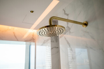Close up of a gold color shower head attached to a wall