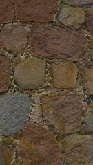 An old stone wall. Masonry. Background of brown stones. The texture of the stone. Vertical image.