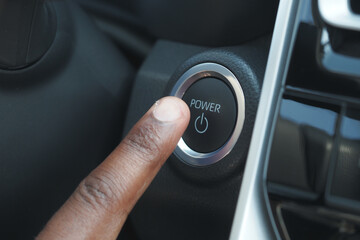 Finger pressing power button in modern vehicle interior