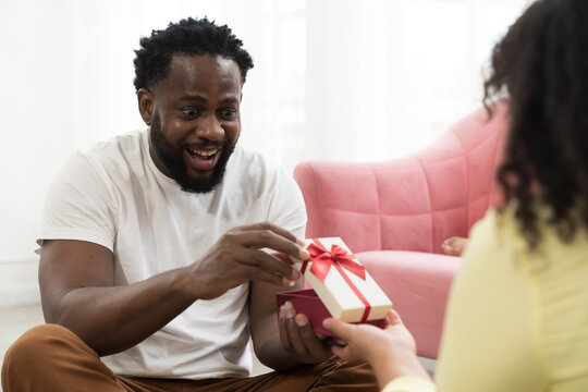 Happy diverse couple family concept. African American male giving gift box or presents gift to asian woman