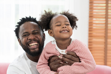 African American father and cute daughter playing together at home. Adult father and little girl...