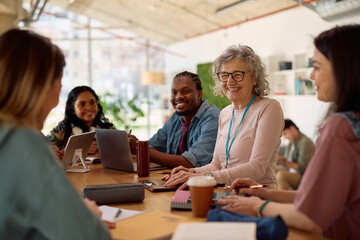 Happy university teacher communicating with her students in classroom.