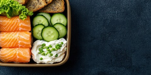 Smoked salmon, cream cheese, and cucumber slices on rye bread. Breakfast box presentation.