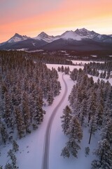Snowy mountain landscape at sunset with winding road through pine trees, winter travel destination, aerial view of picturesque scenery in nature.