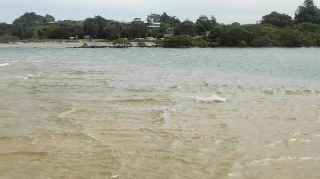 Drone flying over Bellinger River shallow waters, Urunga in Australia. Aerial, low flight