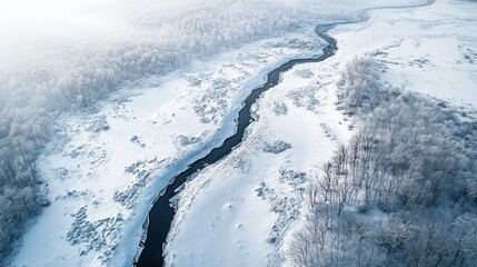 Aerial view of snowy river winding through winter forest