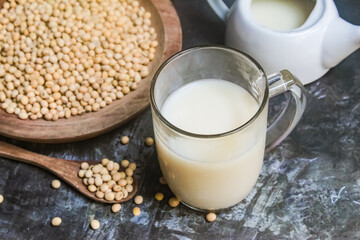 a glass of soy milk with soy beans on the table
