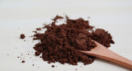 Coffee powder on wooden spoon isolated on wooden background