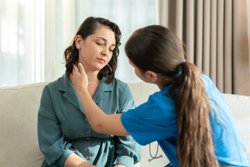 Fototapeta premium Nurse examining woman's neck during home visit