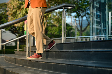 Close up shot of businessman in trendy red sneakers walks down stairs