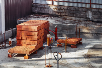 A monolithic slab foundation is being constructed in a wooded area with materials arranged nearby.