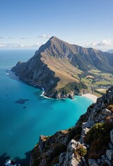 Fototapeta premium A breathtaking view of a turquoise sea meeting rugged cliffs and a distant mountain peak under a clear blue sky