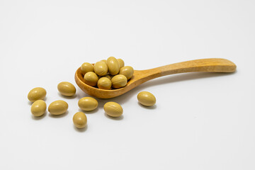Cream colored vitamin capsules in wooden spoon
