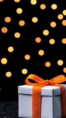 Elegant gift box with an orange ribbon against a blurred festive background.