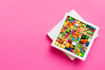 Set of different sweet candy in a paper box with a satin ribbon on a colored background. Holiday concept