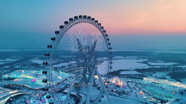 Aerial drone shot of snowflake Ferris wheel at sunset with beautiful colors at Harbin Ice Festival in Heilongjiang, China