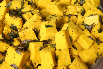 Dhokla: traditional national dish of Gujarati cuisine, India. Plate with yellow homemade spicy dhokla cakes. Indian vegetarian food, cuisine. Street food in Gujarat, yammy pastry. Pieces of dhokla