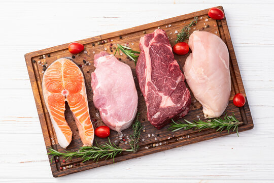 Mix of raw meat and fish . Salmon , beef , pork , chicken staek . Top view