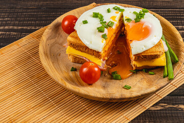 Delicious sandwich with fried eggs and fresh tomatoes served on wooden plate