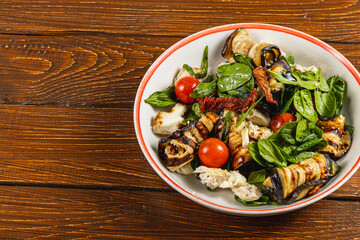 Fresh summer salad with grilled vegetables and chicken on wooden table
