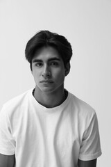 Black and white casual headshot of handsome young man posing over white background. Vertical.