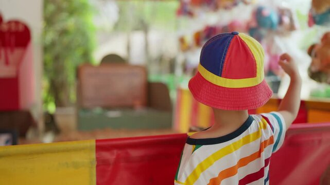 Rear view of a young boy throwing a ball to play a carnival game at an amusement park