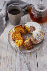 orange cupcake on a white wooden table with a teapot of black tea still life