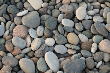 Pebbles of different sizes on pebble beach. Stone texture, background, wallpaper. Beach vacation concept