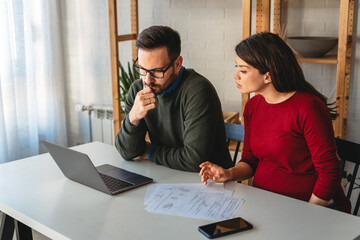 Husband and wife doing paperwork together, paying taxes online on notebook computer