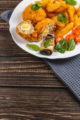Savory platter of stuffed chicken and crispy potatoes on wooden table