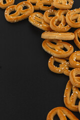 Enjoying crispy pretzels scattered on a black surface with sesame seeds