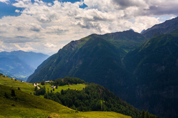 Obraz premium Scattered alpine houses. Beauty of Grossglockner High Alpine Road in Austrias Hohe Tauern National Park, where towering mountains meet rolling meadows.