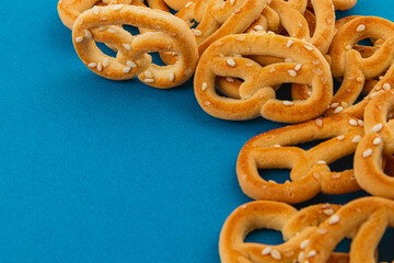 Soft pretzels scattered on a vibrant blue surface with sesame topping
